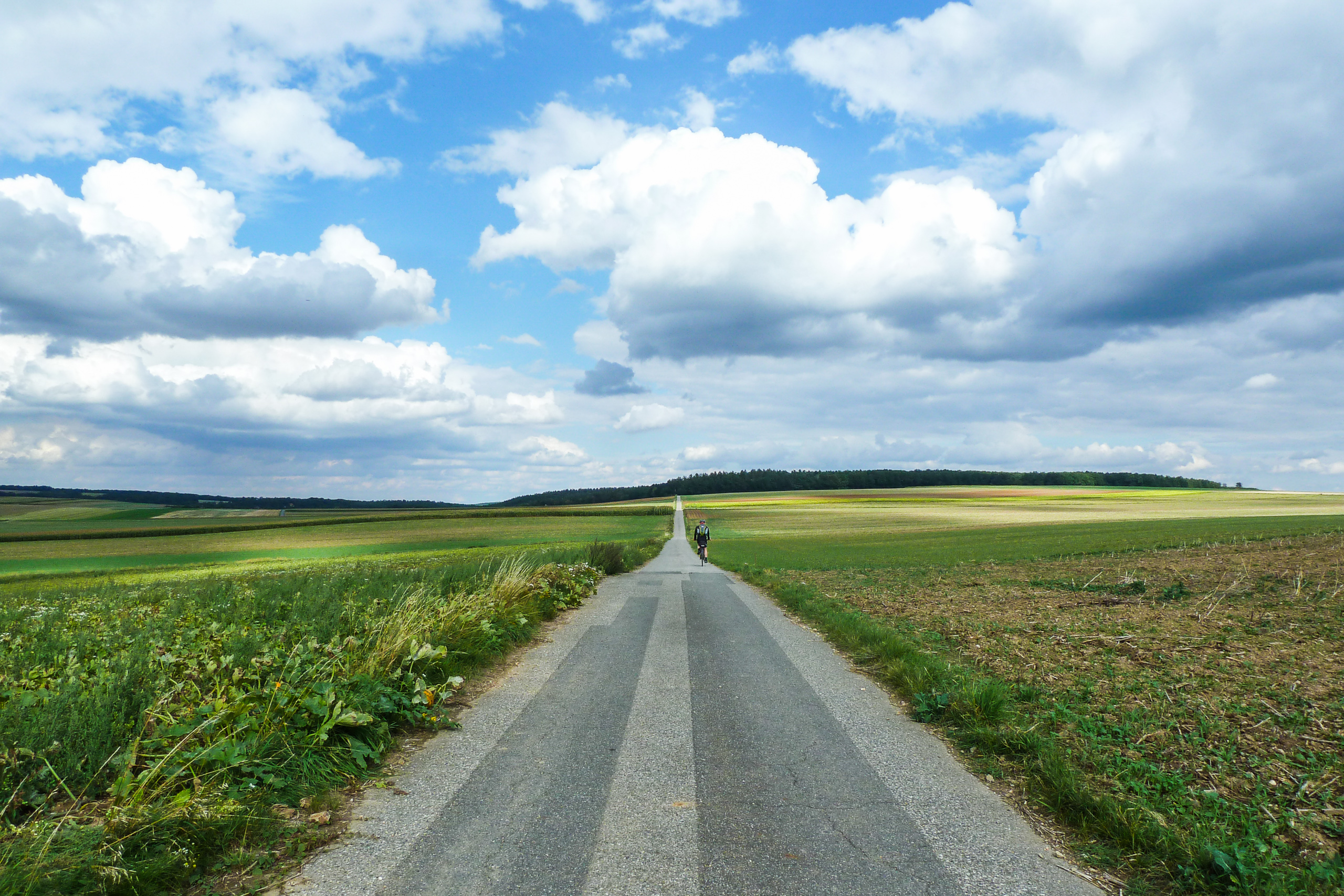 Schnurgerade Landstraße unter mächtigen Wolken